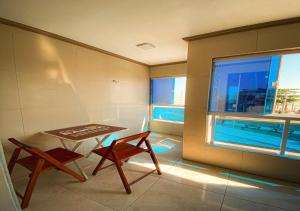 Habitación con mesa, 2 sillas y ventana en Flats Bahia, en Coruripe