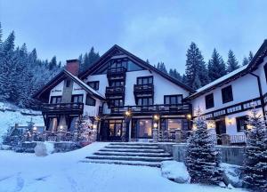 a large house in the snow with christmas trees at Pensiunea Poiana Izvoarelor in Vatra Dornei