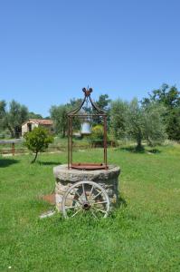 una campana seduta sopra una ruota di pietra in un campo di Casetta del Pozzo a Seggiano