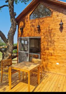 Cabaña de madera con mesa y sillas en una terraza en Haasienda - Nido del Loro - Casa de Arbol, 