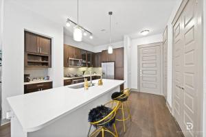 a kitchen with a white counter and two yellow stools at Downtown Houston Deluxe King Suite with Spa Amenities, Pool and Free Parking in Houston