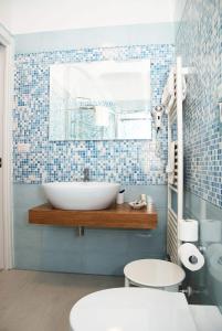 uma casa de banho com um lavatório branco e azulejos azuis em Falli Exclusive Rooms and Breakfast em Porto Cesareo