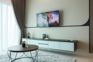 uma sala de estar com uma mesa e uma televisão na parede em Greenfield Residence, Bandar Sunway by The Comfort Zone em Petaling Jaya