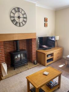 a living room with a fireplace and a clock on the wall at Star Cottage - Harbottle - Nr Rothbury - Northumberland in Morpeth