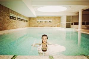 una mujer nadando en una piscina en Crocus Gere Bor Hotel Resort & Wine Spa en Villány