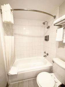 y baño con bañera blanca y aseo. en Lincoln Hotel Monterey Park Los Angeles, en Monterey Park