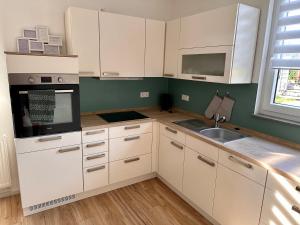 a kitchen with white cabinets and a sink at Ferienwohnung Storchennest in Eisfeld
