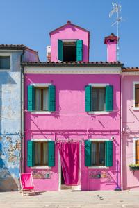 un edificio rosa con persiane verdi di Flora Cottage Guesthouse Burano a Burano