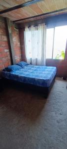 a blue bed in a room with a brick wall at Casa campó in Cali