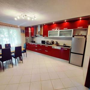 uma cozinha com armários vermelhos, uma mesa e cadeiras em Villa Nika em Škrip