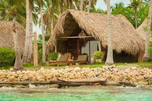 Hotel Isla Mucura في جزيرة موكورا: منتجع بسقف من القش وكراسي وماء