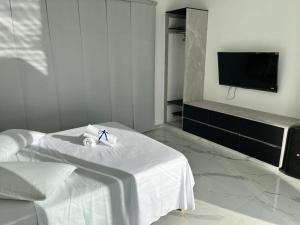 um quarto branco com uma cama e uma televisão de ecrã plano em Hillside , hermosa casa, cerca de centro comercial em Restrepo