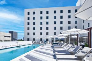 una piscina con sedie a sdraio e ombrelloni accanto a un edificio di AC Hotel by Marriott Miami Aventura ad Aventura