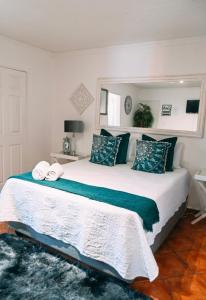 a bedroom with a large white bed with blue pillows at Zhantique Airport Guest House Unit 5 in Boksburg