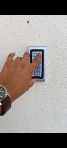 una mano está presionando un botón en una pared en King bed-Studio Room Near "al bateen" Abudhabi, en Abu Dabi
