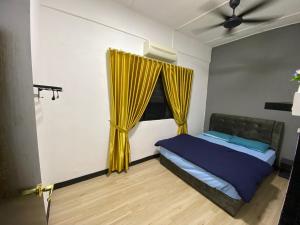 a bedroom with a bed with yellow curtains and a window at Pagoh Town Homestay in Pagoh