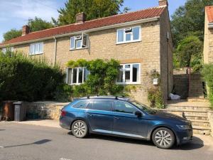 un coche azul estacionado frente a una casa en St Anthony’s, bright perkily decorated 3 bedroom house en Ampleforth