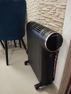 a black radiator sitting next to a blue chair at Gama LUX in Perea