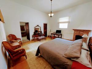 a bedroom with a bed and a chair and a desk at Suites Santo Domingo in San Miguel de Allende