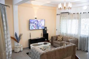 uma sala de estar com dois sofás e uma televisão em Hypo Guest Lounge em Iaundé