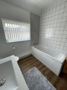 a white bathroom with a tub and a sink at Charlesworth House in Crewe