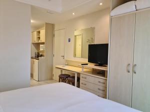 a bedroom with a bed and a desk with a television at Jurerê Beach Village Studios Para Temporada in Florianópolis