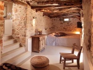 a bedroom with a bed and a chair and stairs at Themonies Luxury Suites in Chora Folegandros