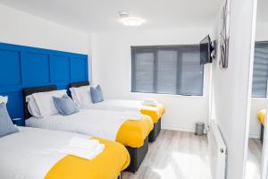 a room with three beds with yellow and white at 8 Beds, 3baths Perfect For Contractors & Teams in Basingstoke