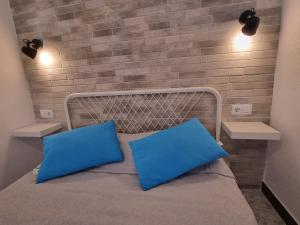 アリカンテにあるApartamentos Alicanteのベッドルーム1室(青い枕とレンガの壁付)