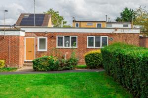 a brick house with a solar roof and some bushes at Wow 8beds 3bath Home Contractors Choice Parking in Basingstoke