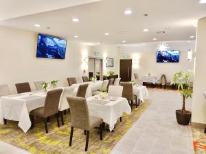 a restaurant with white tables and chairs and tv on the wall at Lincoln Hotel Monterey Park Los Angeles in Monterey Park