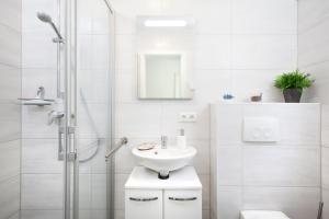La salle de bains blanche est pourvue d'un lavabo et d'une douche. dans l'établissement Ferienhaus Sturmmöwe Zingst, à Zingst