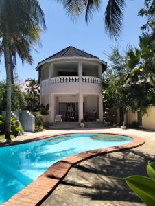 a villa with a swimming pool in front of a house at Diani Hideaway Beach Villa in Galu