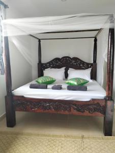 a wooden bed with pillows in a room at Diani Hideaway Beach Villa in Galu