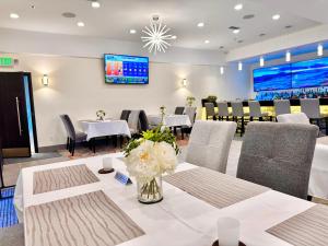 a dining room with tables and chairs and a tv at Lincoln Hotel Monterey Park Los Angeles in Monterey Park