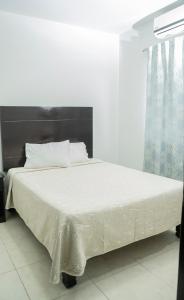 uma cama com lençóis brancos e almofadas num quarto em Hotel Tampico Express em Ciudad Madero