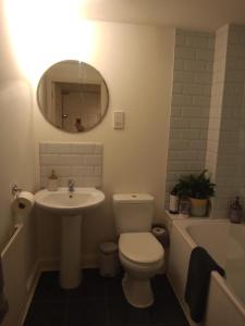 a bathroom with a toilet and a sink and a tub at The Eaves, Glastonbury High Street 2 bed 2 bathroom apartment in Glastonbury