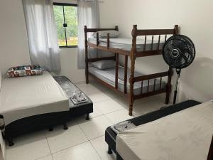 um quarto com 2 beliches e uma ventoinha em Casa Temporada , Parque mambucaba em Angra dos Reis