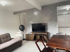 a living room with a couch and a television at Casa Temporada , Parque mambucaba in Angra dos Reis