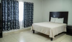 Schlafzimmer mit einem Bett und einem Fenster mit Vorhängen in der Unterkunft Hotel Tampico Express in Ciudad Madero