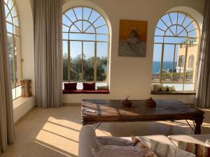 uma sala de estar com uma mesa e janelas grandes em The Cliff Hotel. em Tel Aviv