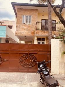 a motorcycle parked in front of a fence with a house at Jamesville-4BHK Villa, Wi-Fi, SmartTV - CityCentre in Bangalore