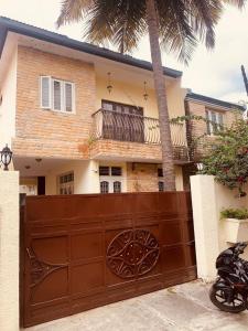 a house with a brown gate and a palm tree at Jamesville-4BHK Villa, Wi-Fi, SmartTV - CityCentre in Bangalore