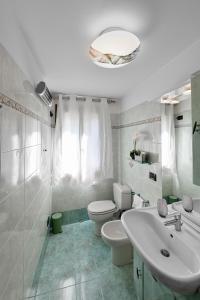 Flora Cottage Guesthouse Burano في بورانو: حمام أبيض مع حوض ومرحاض