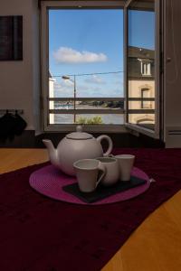 een theepot en twee kopjes op een tafel met een raam bij LE PRIEURE in Dinard