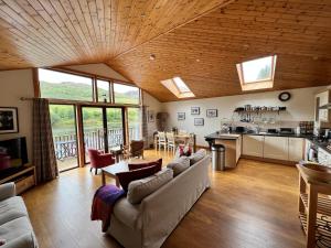 a living room with a couch and a table and a kitchen at Ptarmigan Lodge in Pitlochry