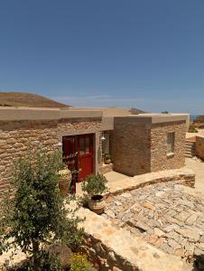 una casa de ladrillo con puerta roja y pasarela de piedra en Themonies Luxury Suites en Chora Folegandros