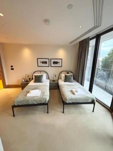 a bedroom with two beds and a balcony at Luxury 2BR Apt at C House Near Buckingham Palace in London