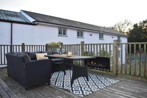 un patio con mesa, sillas y chimenea en Luxury 2-Bed Barn Conversion in Llansteffan, en Carmarthen