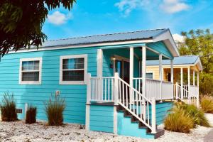 niebieski dom z białą werandą i schodami w obiekcie Pinecraft Blue Heron Tiny Home w mieście Sarasota